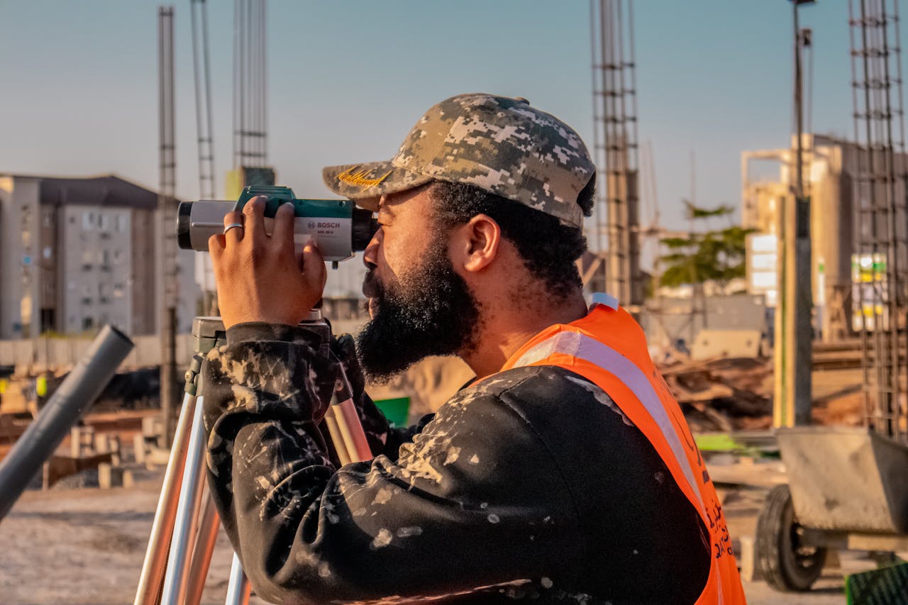 A construction worker uses a theodolite on a building site, capturing precise measurements.